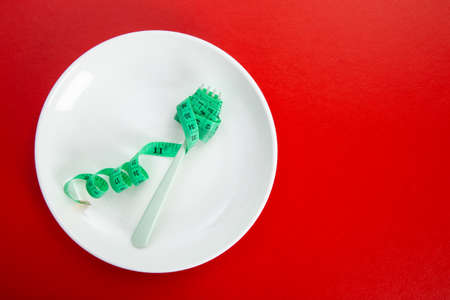 Diet for weight loss concept. Proper nutrition. Empty plate with fork and measuring tape.の写真素材