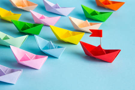 Leadership concept. Red leader paper ship leading among others on blue background.の写真素材