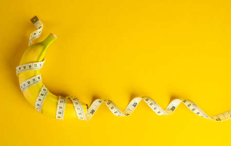 Diet concept. Banana and tape measure on yellow backgroundの写真素材