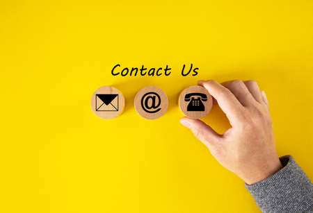 Wooden cubes with mail, phone and email icons on table, yellow background. Contact U sand Customer...