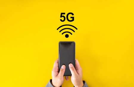 Male hand holding smartphone with 5G signalの写真素材