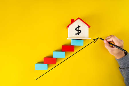 Businessman drawing an arrow up above the houses.