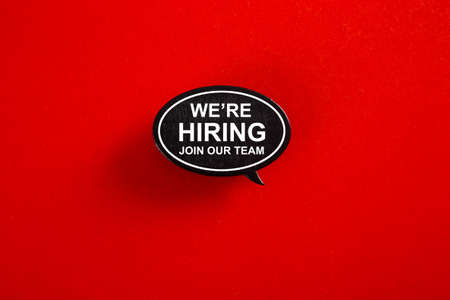 WE'RE HIRING in speech bubble isolated on red paper background with drop shadow.の写真素材