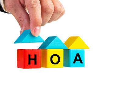 Businessperson's hand placing wooden house block with HOA word isolated on whiteの写真素材
