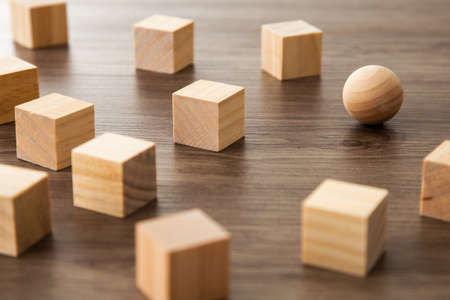 Wooden sphere ball among the wood cubes, different and position in niche market conceptの写真素材
