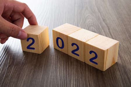 Hand with woodblocks cubes with a number 2022 wooden background. new year 2022 concept.の写真素材