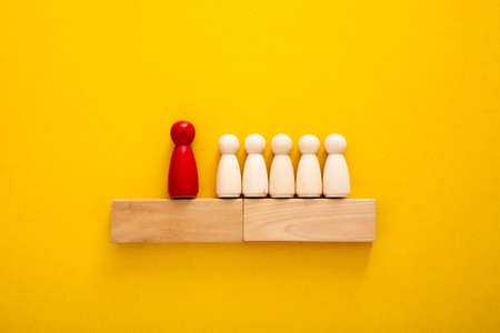 Wooden figures on yellow background. Concept of supremacy leaderの写真素材