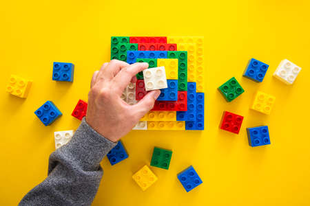 hand stacking up the colorful plastic blockの写真素材