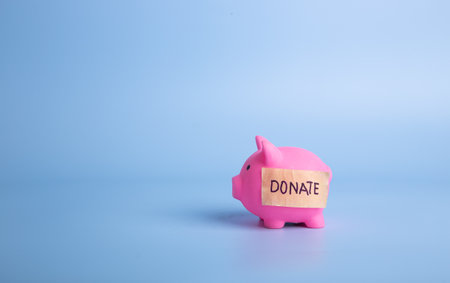 Pink piggy bank with donate word on a blue background. Donation and charity conceptの写真素材