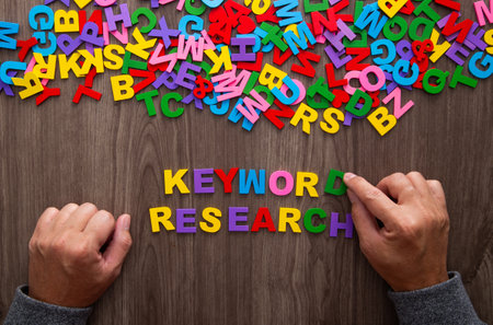 Hand arrangging color letters of the alphabet and the word Keyword Researchの写真素材