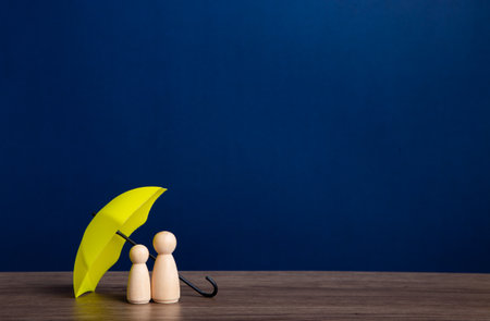 Umbrella and wooden doll figures. Insurance coverage concept.の写真素材