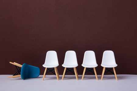 Row of white chairs and a blue one falling down.
