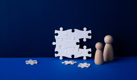 Two business people facing an incomplete jigsaw puzzle representing problem solving, recruitment and business insuranceの写真素材