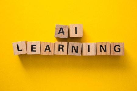 Wooden cubes composing the words ai and learning on a yellow background, representing artificial intelligence and machine learning conceptsの写真素材