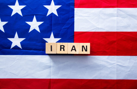Wooden blocks spelling iran on crumpled american flag representing international relations and...
