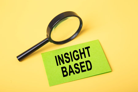 Magnifying glass and green note on a yellow background signifying business analysis and discovery