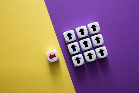 One red arrow standing out from many black up arrows on a yellow and purple backgroundの写真素材