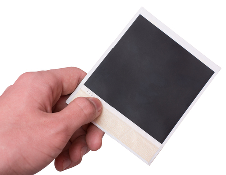 Aged retro polaroid photo frame in hand on whiteの写真素材