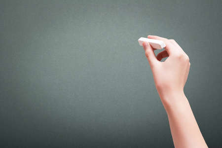 Hand holding white chalk and starting to write on blackboardの写真素材