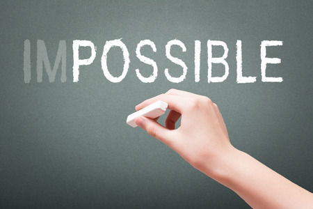 Hand writing with chalk impossible concept on blackboardの写真素材