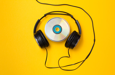 Black headphones with CD disc on yellow backgroundの写真素材
