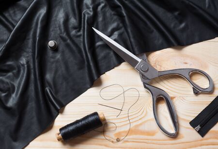 Cutting textile or fine cloth with a taylor scissors on wooden table. Sewing toolsの写真素材