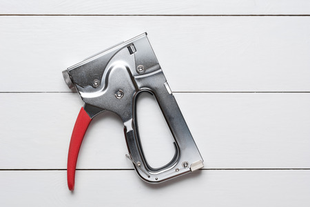Large tacker stapler gun on white wooden floorの写真素材