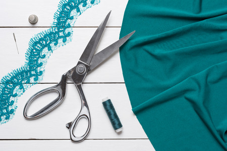 Cutting textile or fine cloth with a tailor scissors on white wooden table. Sewing toolsの写真素材