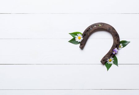 Horseshoe, used and with rust, on white painted wood, symbol for good luck, background with copy spaceの写真素材