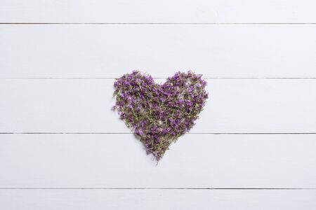 Heart made of thymes on white wooden table backgroundの写真素材