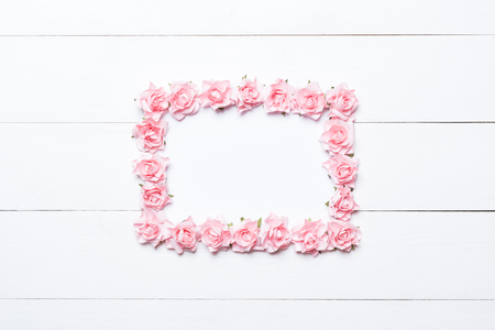 Pink rose frame over white wooden background with empty copyspaceの写真素材