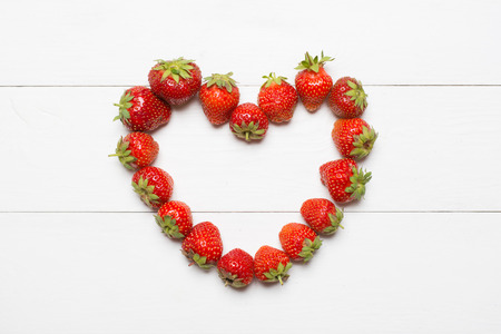 Strawberry heart on white wooden table conceptの写真素材