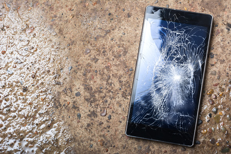 Broken Phone with cracked screen concept  on wet concreteの写真素材