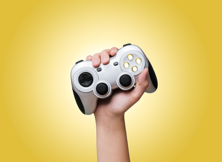 Game controller in hand raised up over yellow background