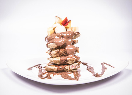 Pancakes with apples covered with fresh fruits on top (banana, peach, apple)の写真素材