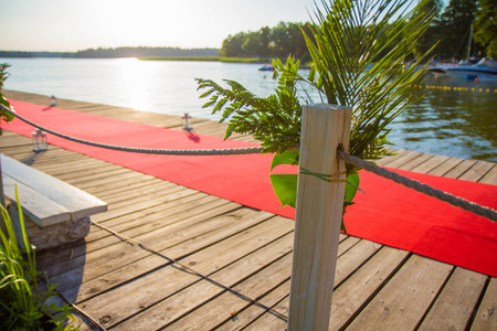 A wooden pier decorated with a red carpet, flowers and lampsの写真素材