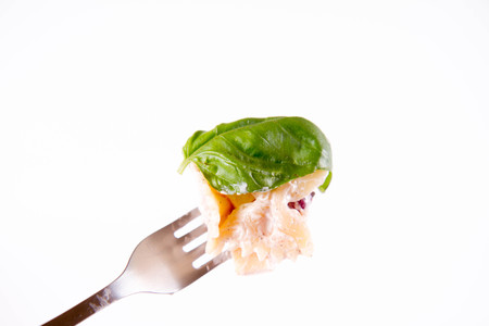 Pasta salad with cheese, ham, kidney beans and mayonnaise on a fork