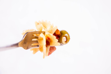 Farfalle pasta with sun dried tomatoes, ham and olives on a white backgroundの写真素材