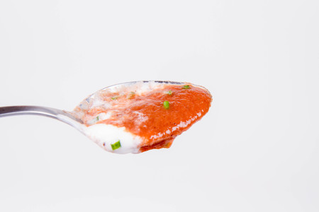 Beetroot cream soup decorated with yogurt and chives being eaten with a spoonの写真素材