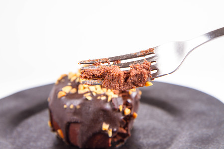 Rum ball decorated with chocolate and nuts on a black plate