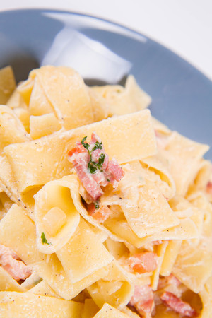 Pappardelle Carbonara on a blue plate on a white backgroundの写真素材