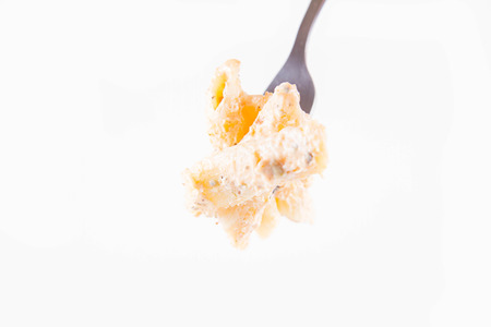 Pasta eaten with a fork - penne with cream sauce on a white backgroundの写真素材