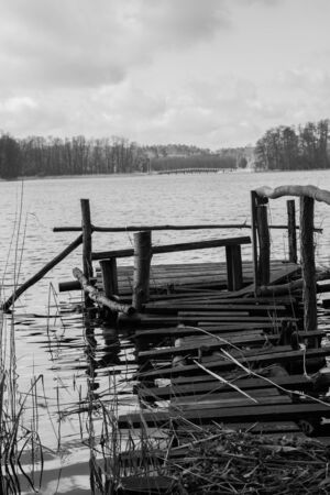 Bridge on a lakeside surrounded with reeds with another bigger bridge seen in the distanceの写真素材