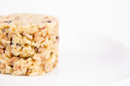 Risotto with button mushroom and bacon on a plate on a white backgroundの写真素材