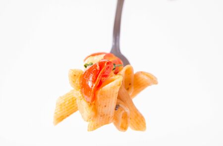 Penne with tomatoes, garlic and mozzarella on a fork on a white backgroundの写真素材
