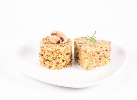 Risotto with button mushroom and bacon - two portions of different shape, on a plate on a white backgroundの写真素材