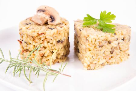Risotto with button mushroom and bacon - two portions of different shape, on a plate on a white backgroundの写真素材