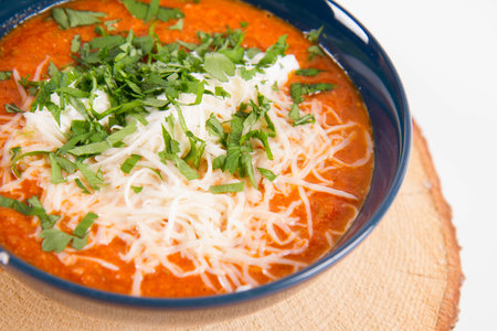 Tomato soup with mozzarella cheese and parsley in a blue bowlの写真素材