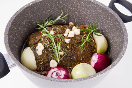 roasted meat with herbs and spices on a frying pan on a white backgroundの写真素材