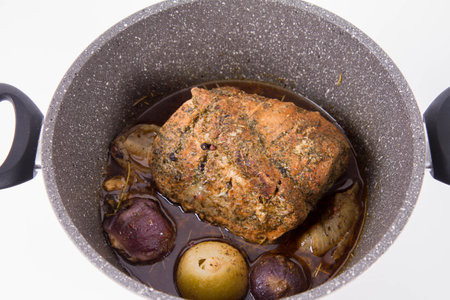 Baked pork with onions in a saucepan on a white backgroundの写真素材